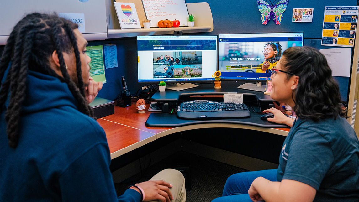 an advisor sitting at a computer looking at the UNCG Starfish program with a student.